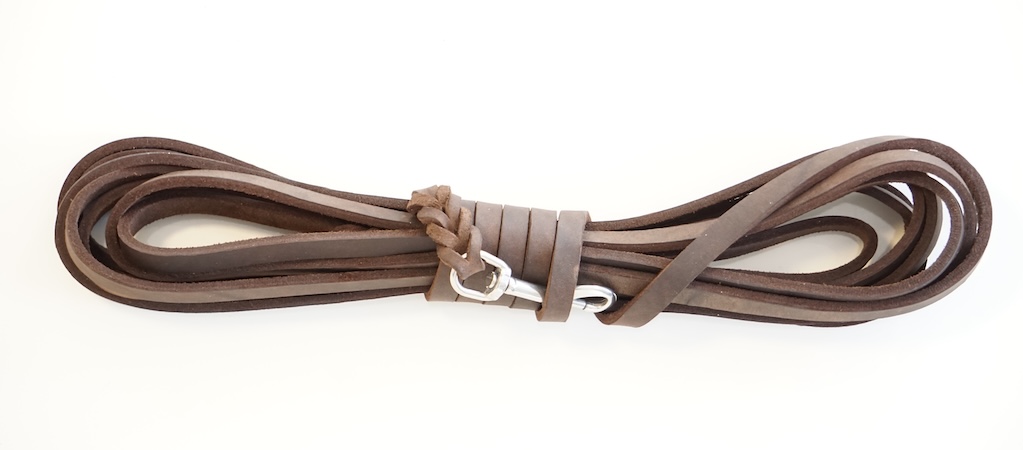 Eine schwarze, zwei orangefarbene und eine gelbe aufgewickelte Mantrailing-Leine.